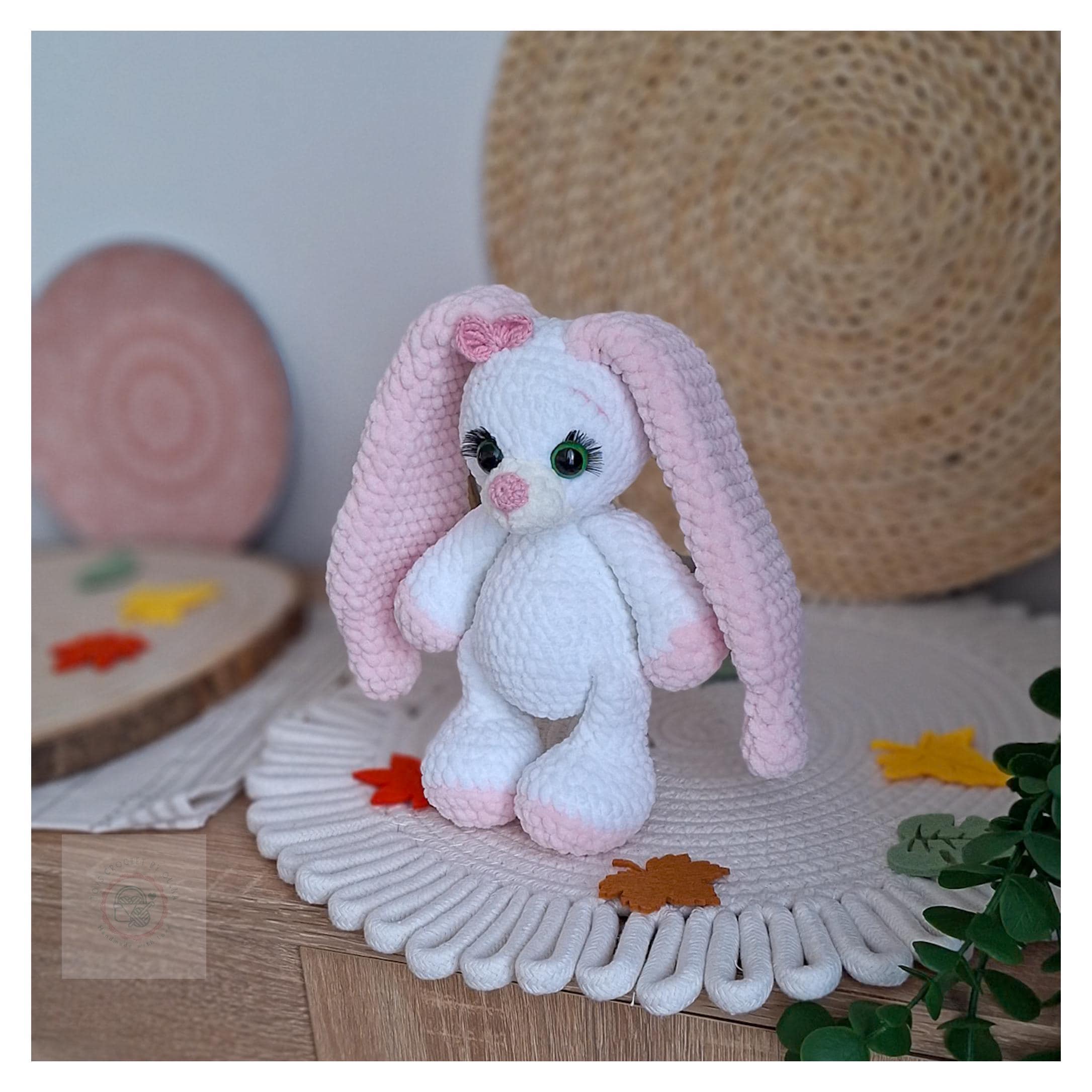 Zbliżenie twarzy króliczka z zielonymi oczkami, różowymi detalami i miękką fakturą włóczki